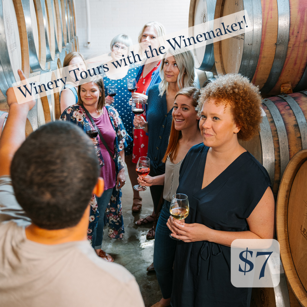 Group of people in a room with wine barrels. Text " Winery Tours with the Winemaker. $7"