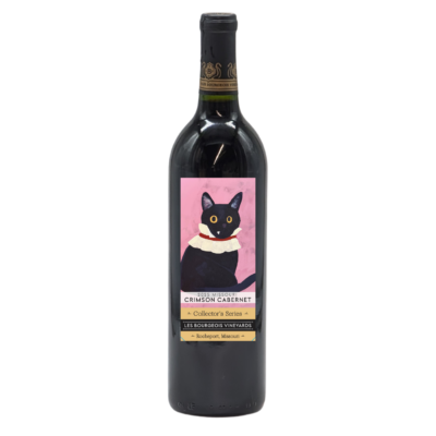 Wine bottle with red wine inside. Has a label depicting a black car wearing a ruffled collar on a pink background. Words say: "2025 Missouri Crimson Cabernet Collector's Series Les Bourgeois Vineyards Rocheport, MO