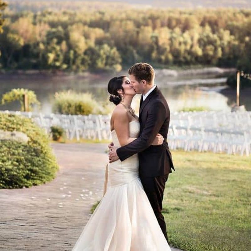 A couple kisses at their wedding outside overlooking the river on The Blufftop at Rocheport