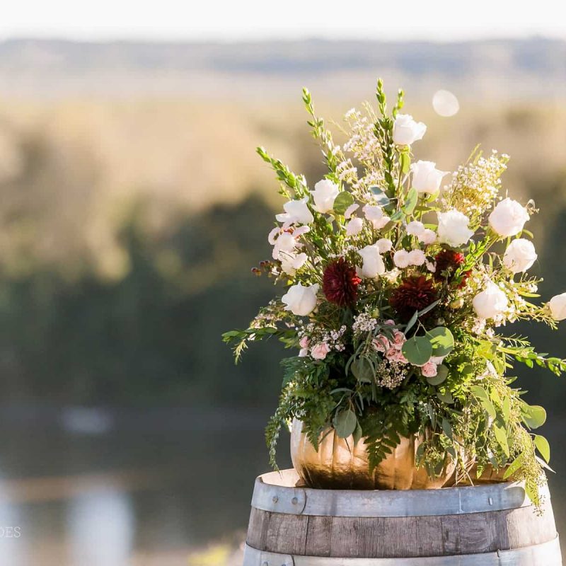 A floral display sits on a barrel overlooking the river